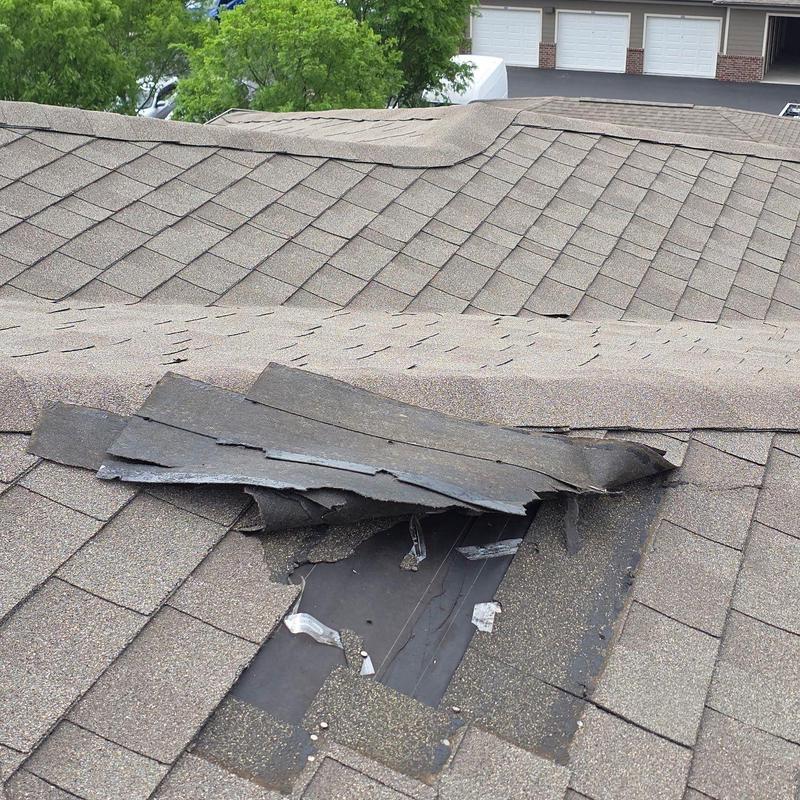Asphalt roofing shingles damaged and lifted on roof