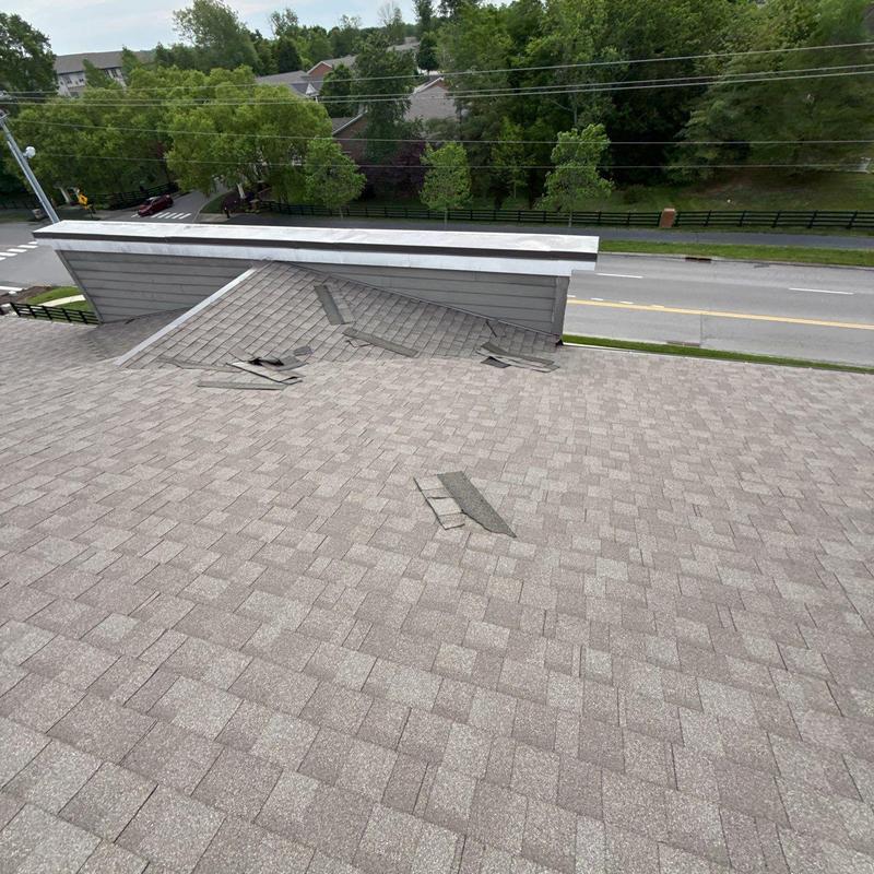 Asphalt shingle roof with storm damage near dormer wall