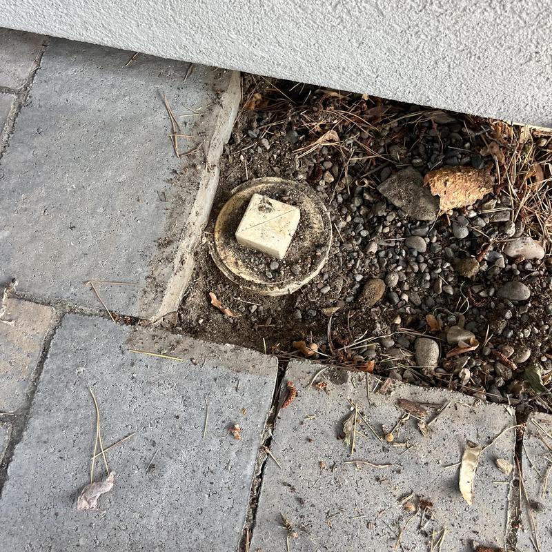 Irrigation valve box exposed in gravel and paving stones Irrigation valve box exposed in gravel and paving stones