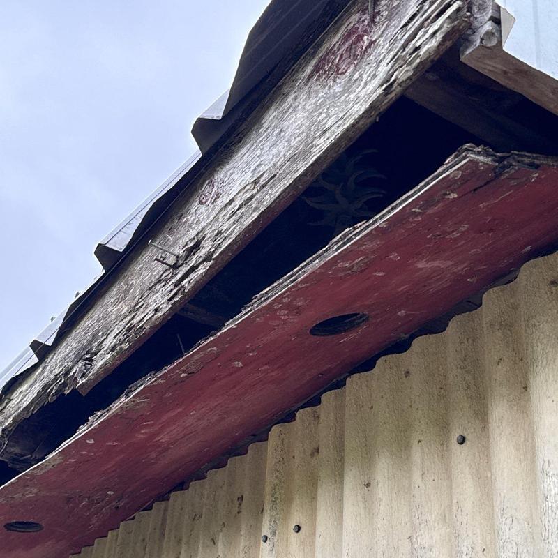 Wooden fascia board with severe rot damage on roof edge