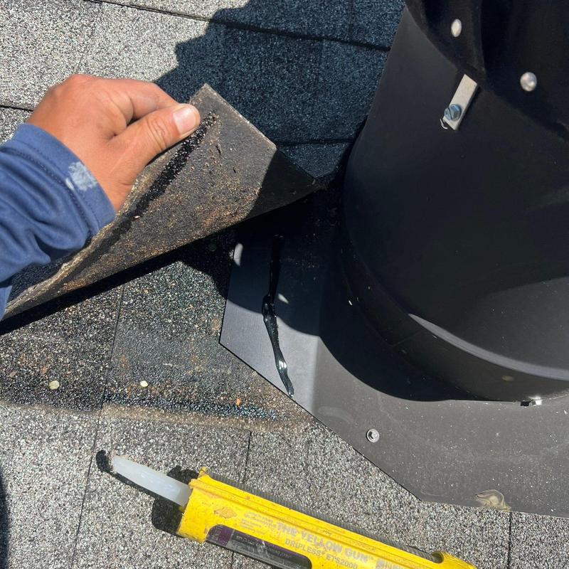 Roof shingles lifted near vent pipe flashing with sealant gun