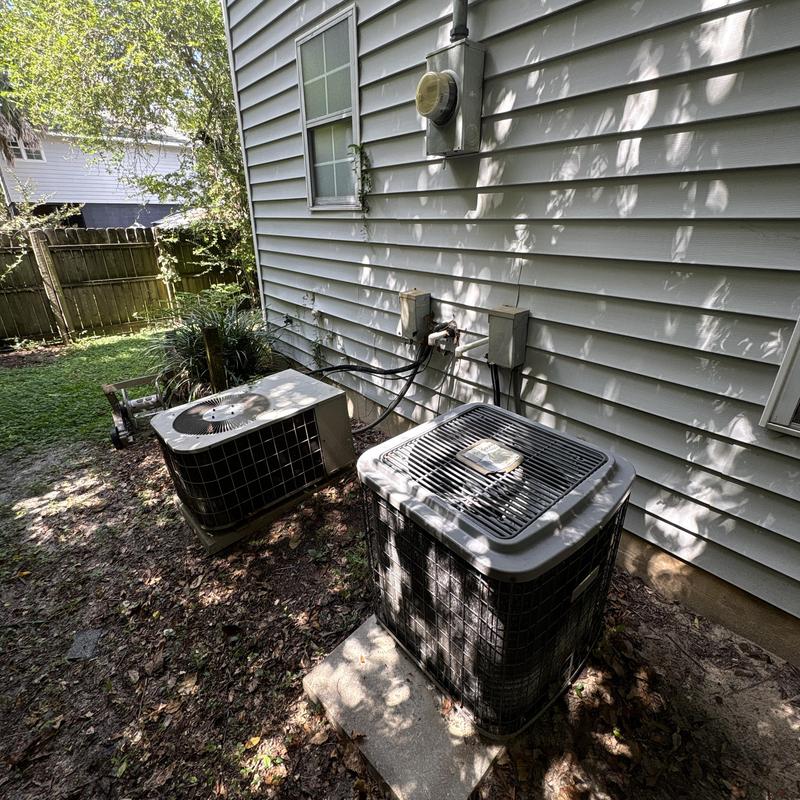 Outdoor AC condenser units by house siding in backyard Outdoor AC condenser units by house siding in backyard