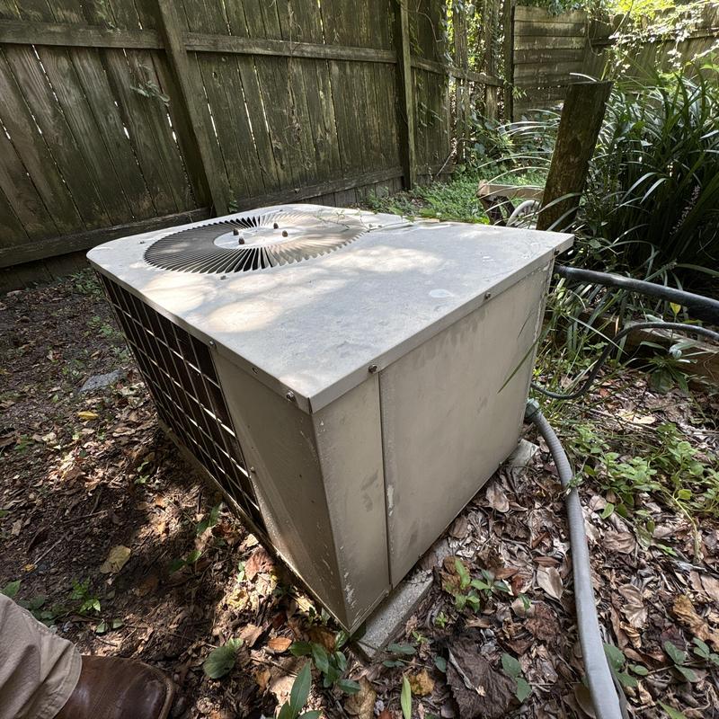 Outdoor air conditioner unit on ground near fence Outdoor air conditioner unit on ground near fence