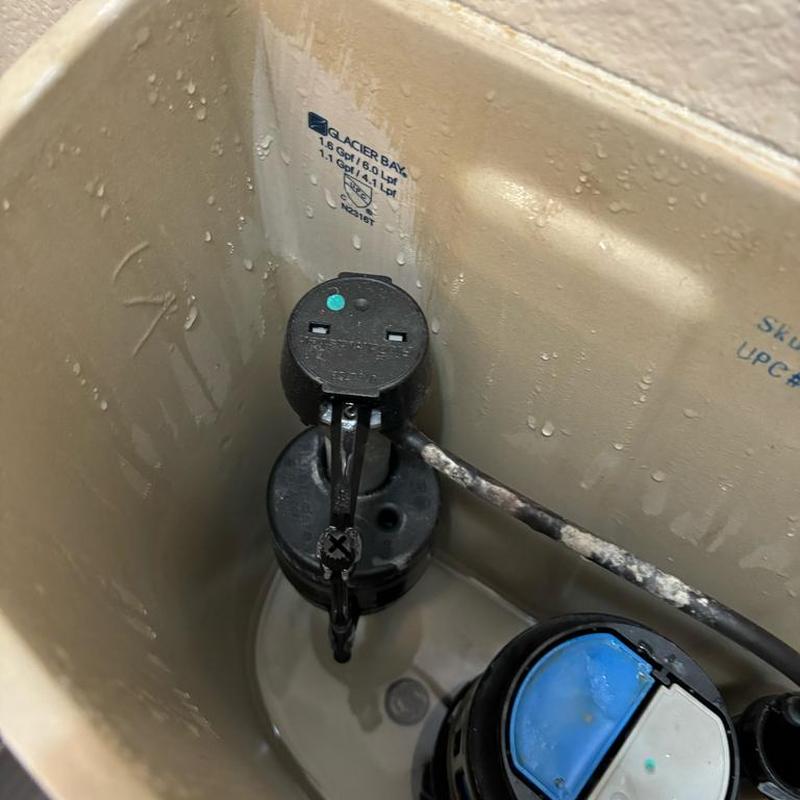 Toilet fill valve inside tank with water droplets
