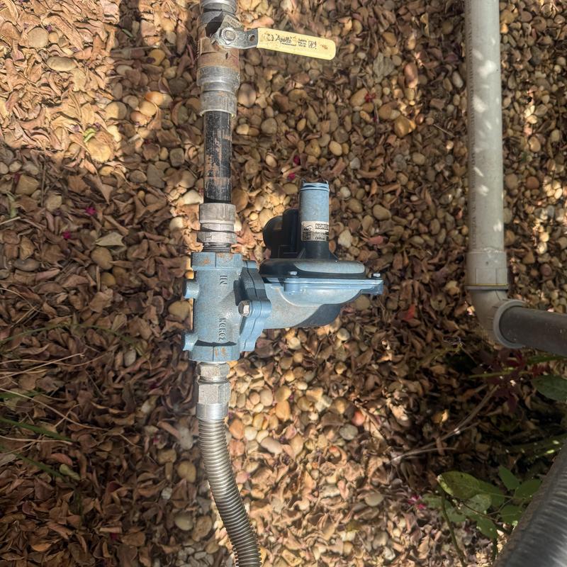 Gas regulator valve with piping outdoors on ground