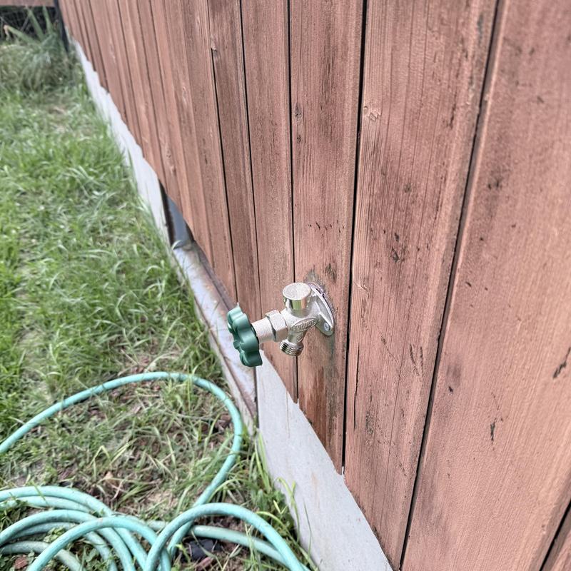 Outdoor water spigot with hose attached to wood siding Outdoor water spigot with hose attached to wood siding
