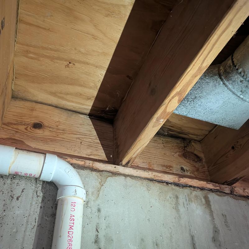 Basement wall wood framing with water staining and piping