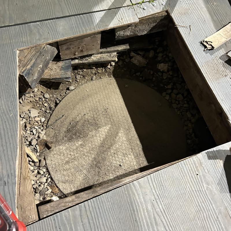 Septic tank lid exposed in floor access hole Septic tank lid exposed in floor access hole