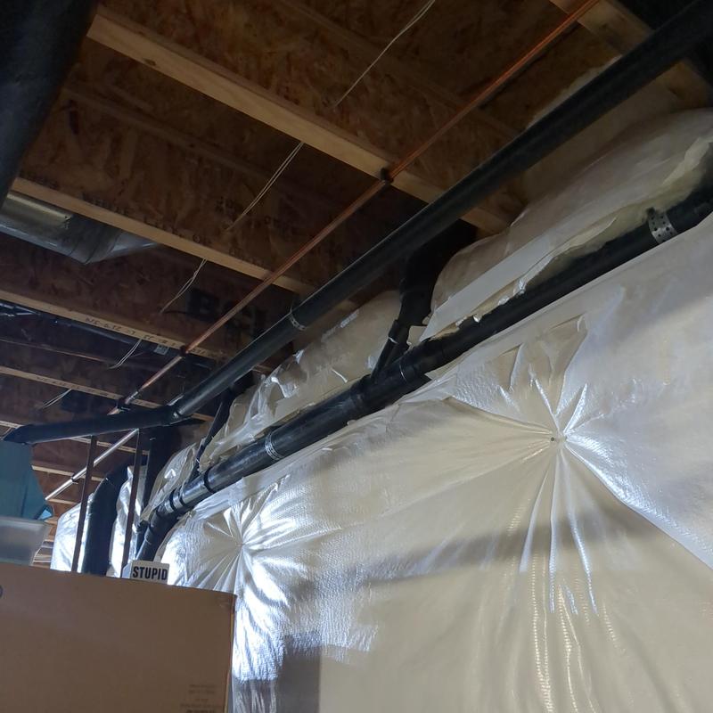 Black PVC radon mitigation pipes installed in basement