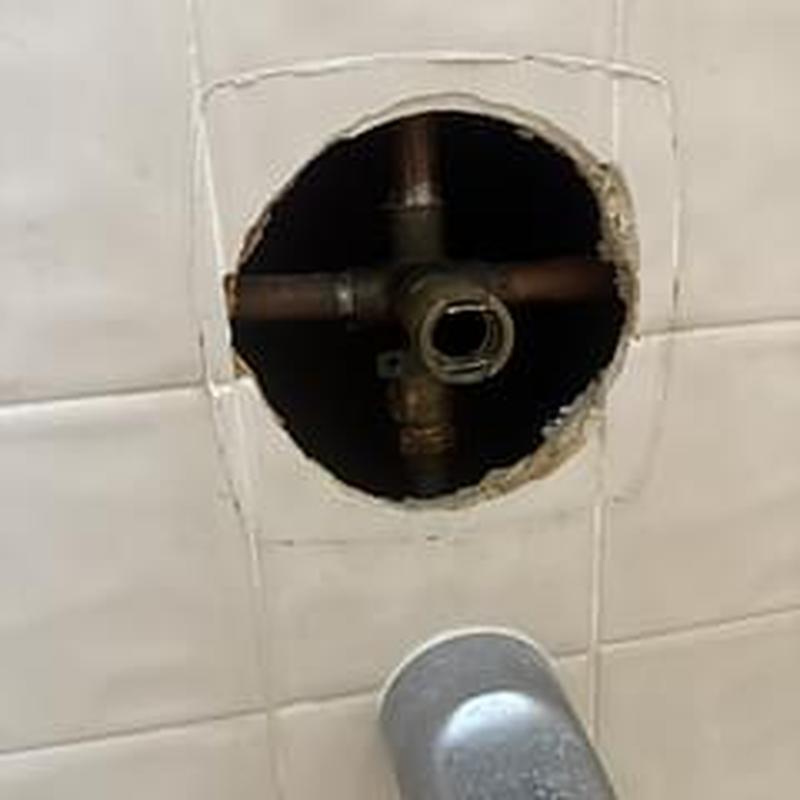 Shower valve plumbing behind tile wall in bathtub area