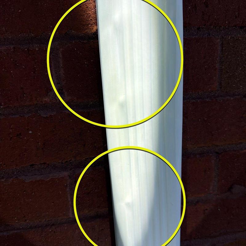 Vinyl downspout dents highlighted on wall background