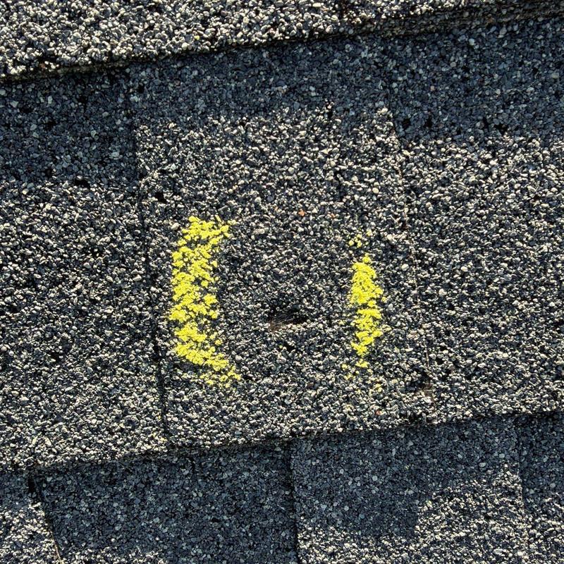 Roof shingle with hail damage marked in yellow paint