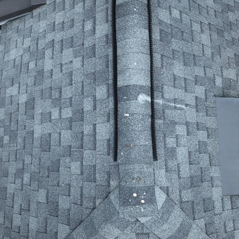 Asphalt shingle roof ridge with hail damage marks
