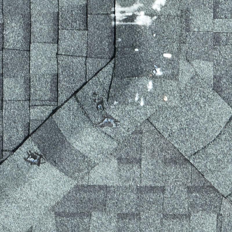 Asphalt roof shingles with hail damage and impact marks
