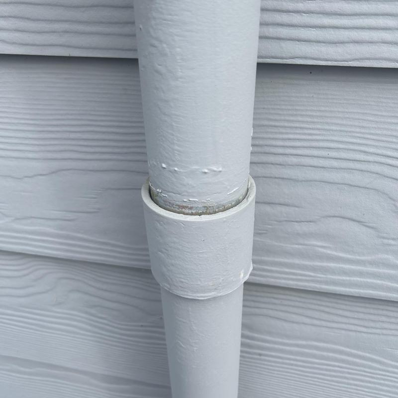 Exterior PVC pipe joint on house siding with paint wear