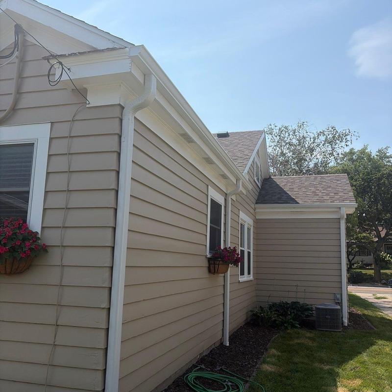 Gutters and downspouts on beige siding house Gutters and downspouts on beige siding house