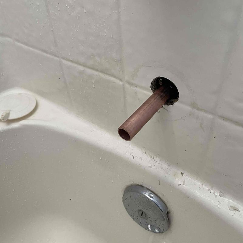 Copper tub spout pipe extension installed above bathtub