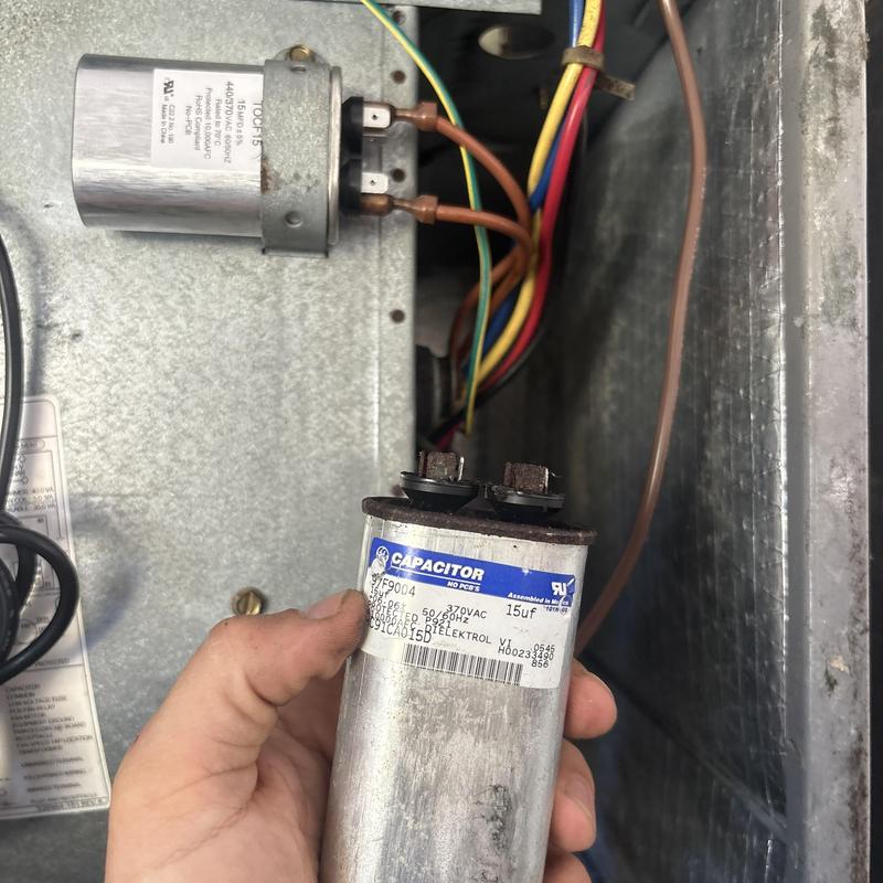 AC capacitor replacement in HVAC unit with wiring visible