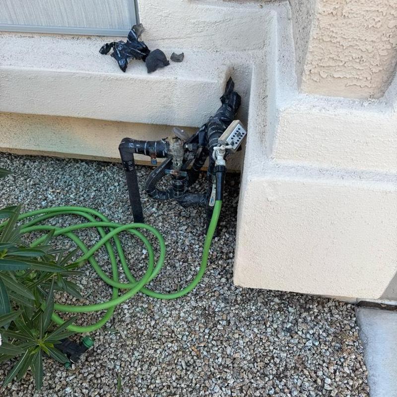 Pressure vacuum breaker with green hose near house wall