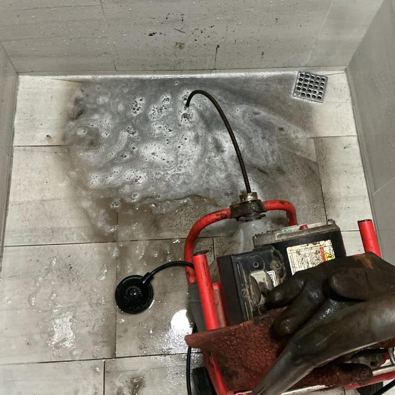Commercial shower drain clearing with powered auger tool