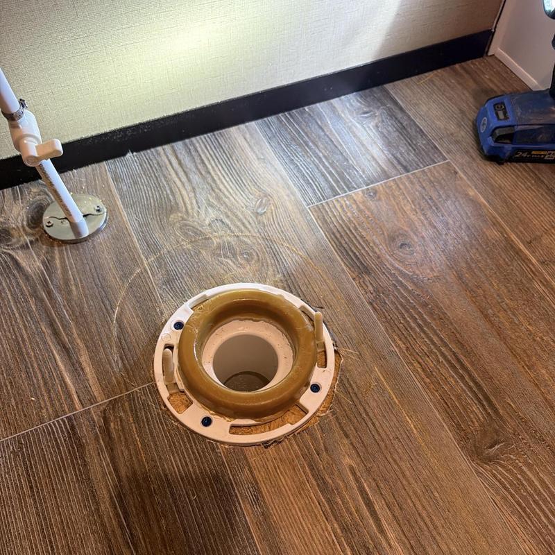 Toilet flange on wood floor with screw holes and wax ring