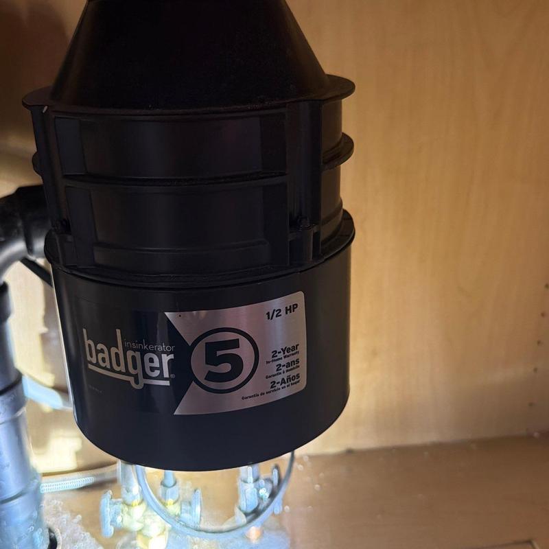 Garbage disposal unit under kitchen sink in wood cabinet