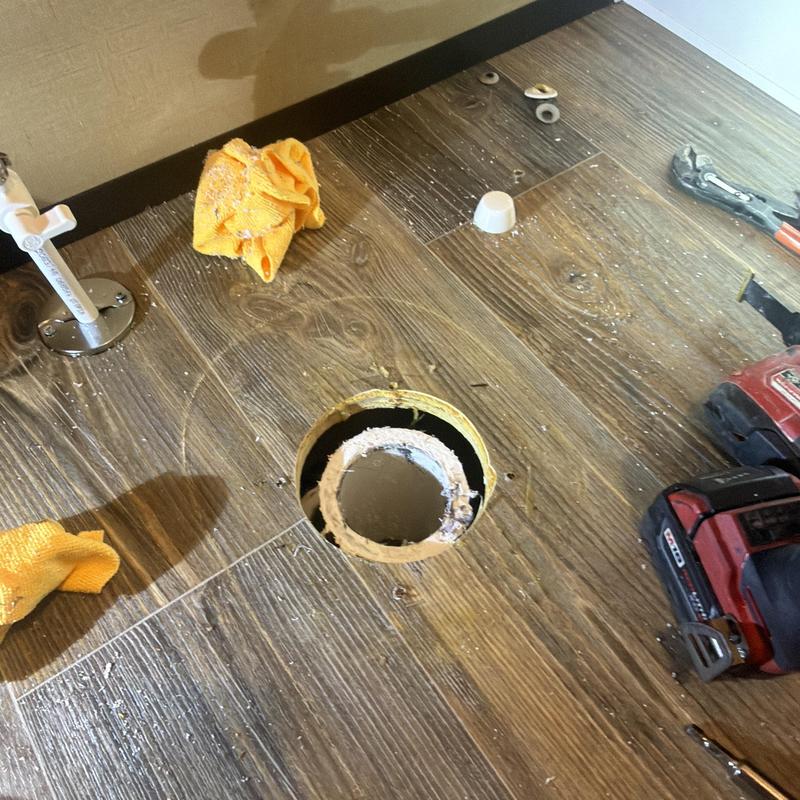 Toilet flange installation on wood floor with tools