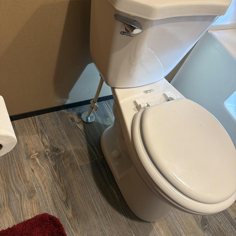 Toilet flange and bowl with closed lid on wood floor