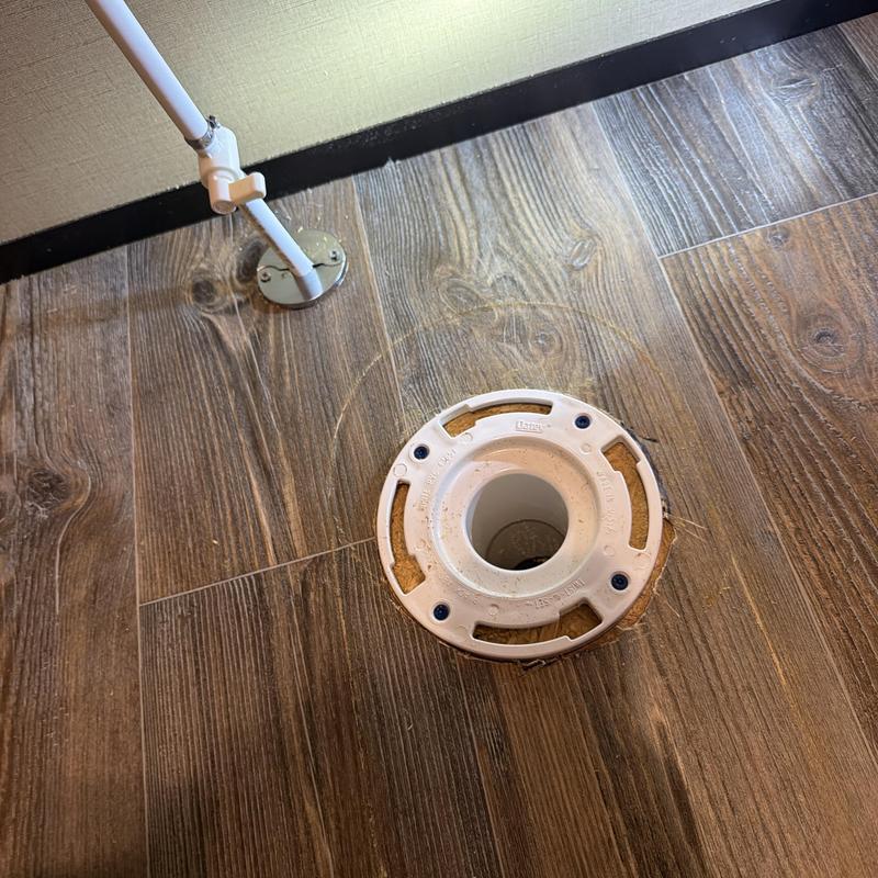 Toilet flange on wood floor with water pipe nearby