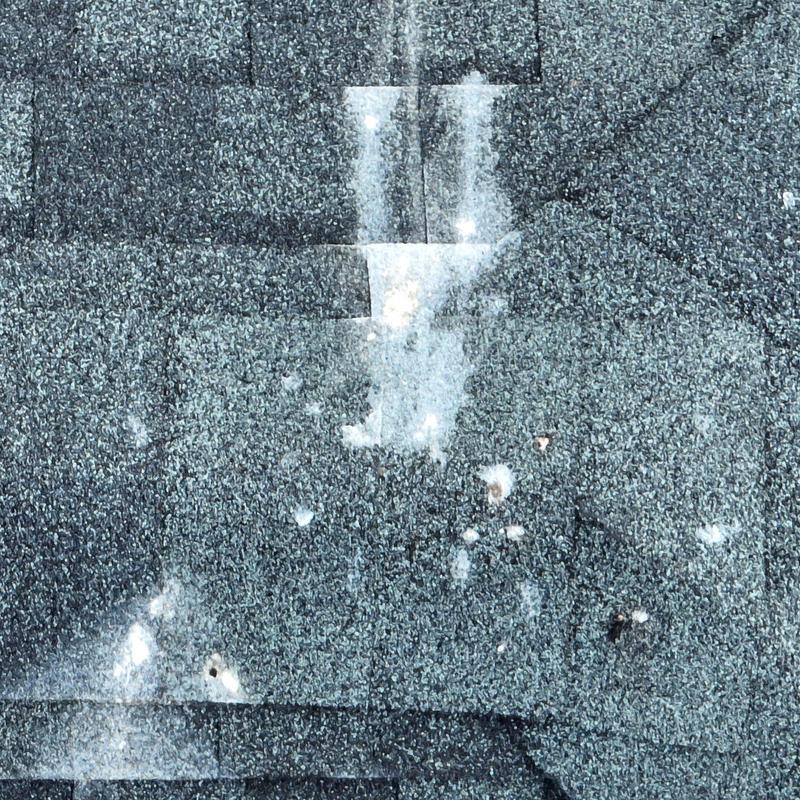 Asphalt roofing shingles with visible hail damage spots