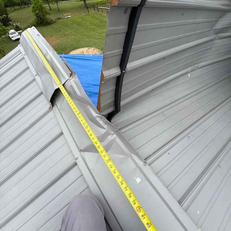 Metal roofing ridge cap with visible damage and measuring tape