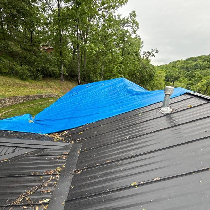 Metal roofing with blue tarp covering damaged area