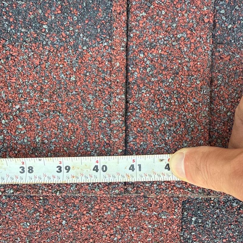 Asphalt roofing shingles with measuring tape and hail damage