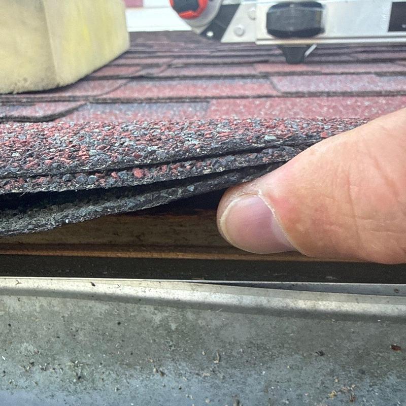 Asphalt roof shingles lifted to show hail damage