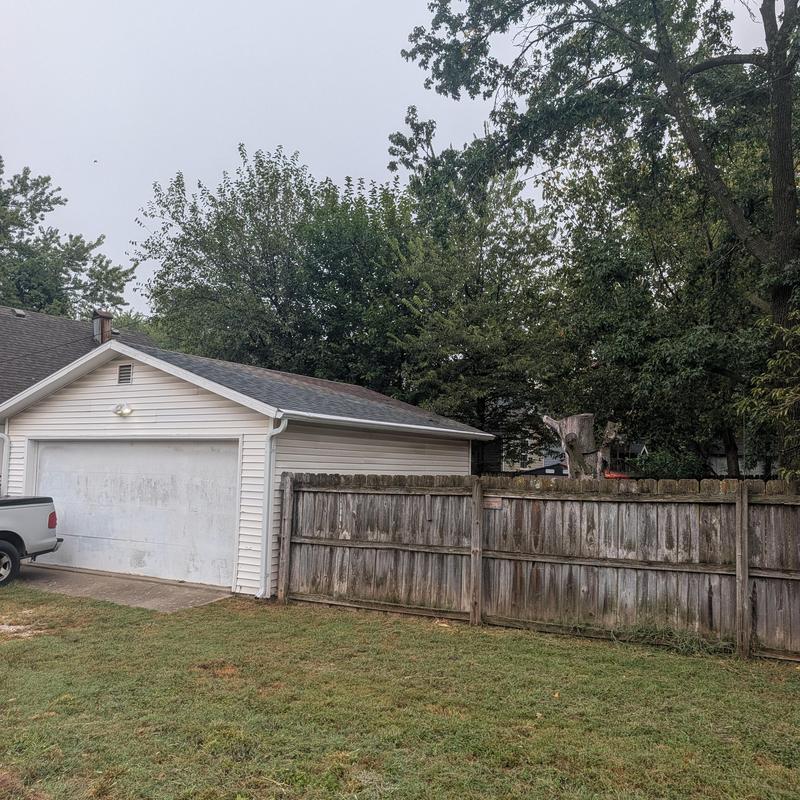 Shed roof, gutters, siding, and downspouts with fence