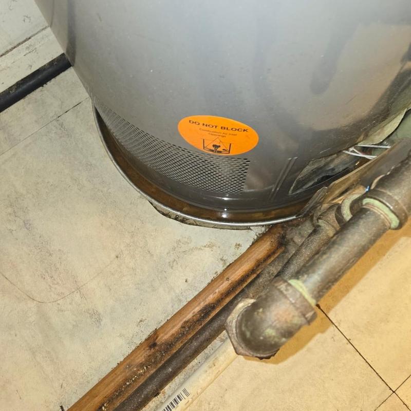 Water heater base with rusted pipes and floor damage Water heater base with rusted pipes and floor damage