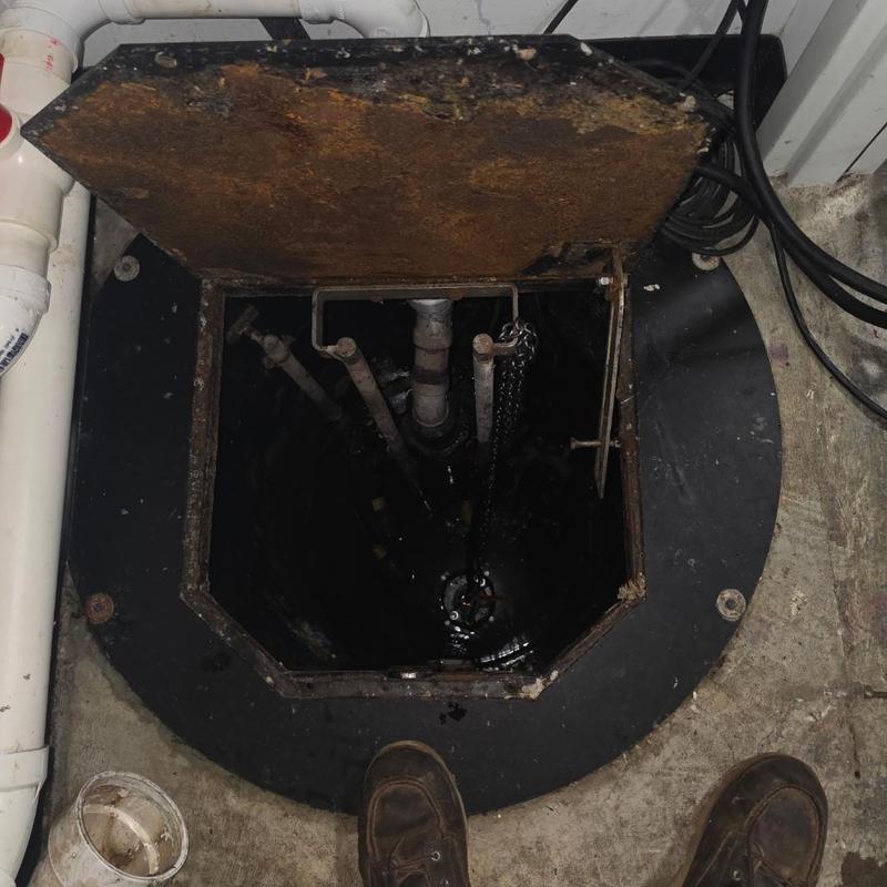 Grinder pump basin with open rusty lid and pipes Grinder pump basin with open rusty lid and pipes