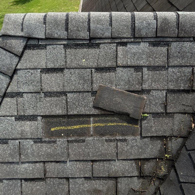 Asphalt roof shingles with hail damage marked for repair
