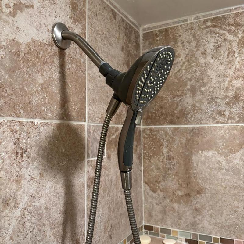 Shower head with handheld attachment in tiled shower