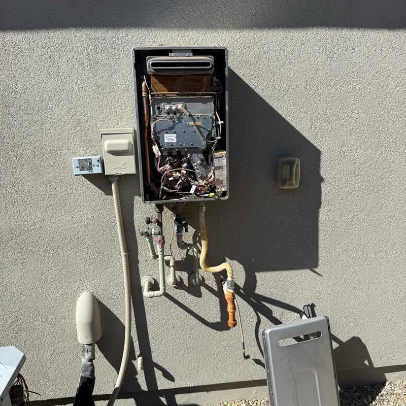 Tankless water heater unit removed from exterior wall