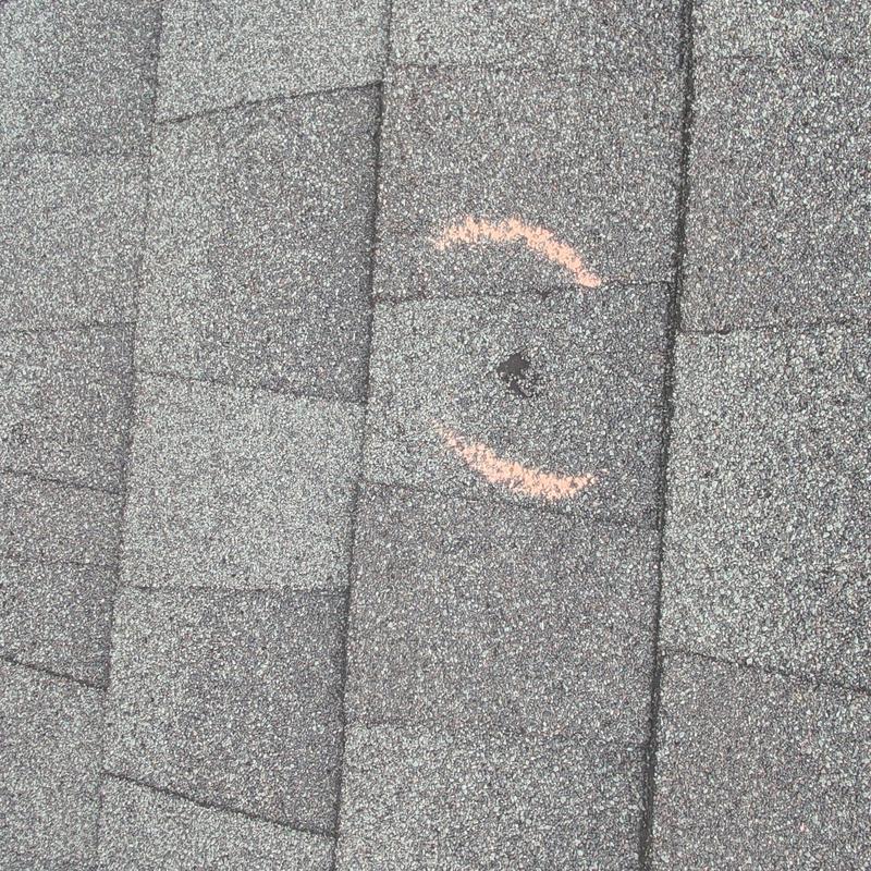 Asphalt shingles with hail damage marked in orange