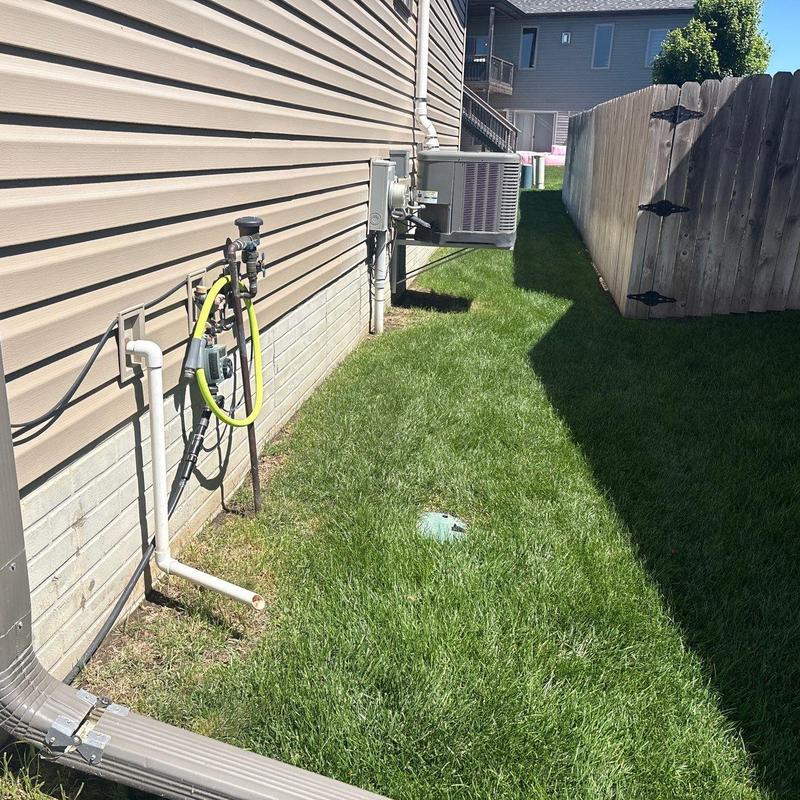 Outdoor HVAC unit and water hose setup by house wall Outdoor HVAC unit and water hose setup by house wall
