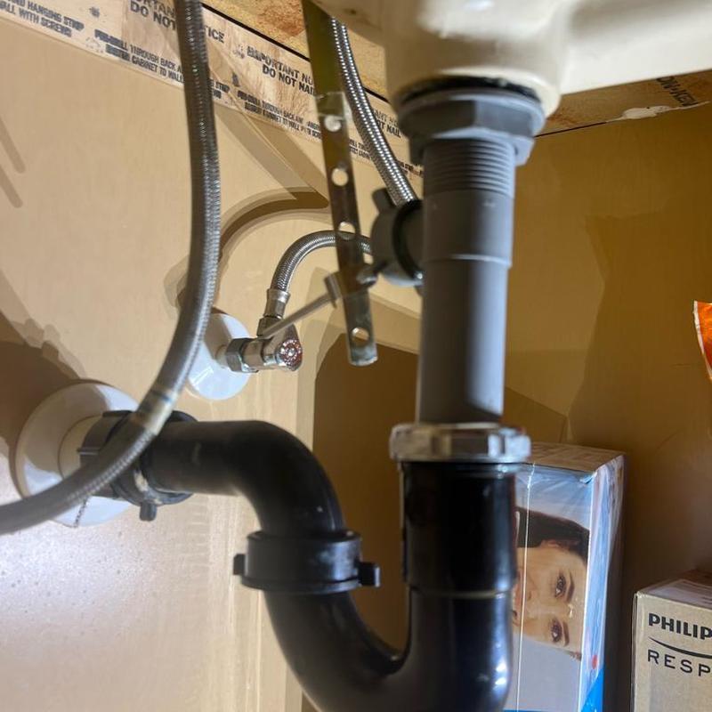 Bathroom sink drain pipe and water supply lines under sink