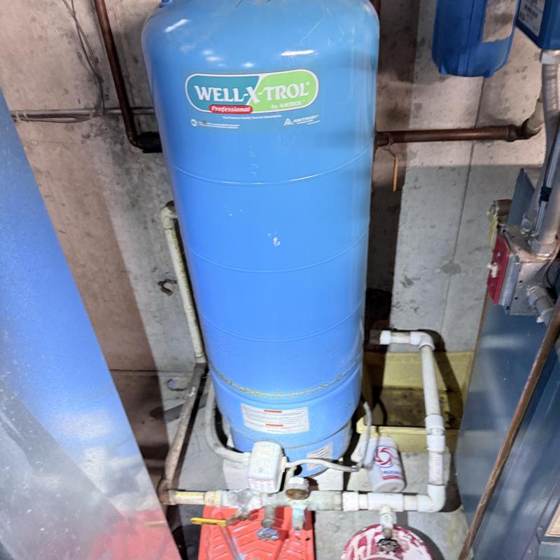 Well tank with connected plumbing in basement setup