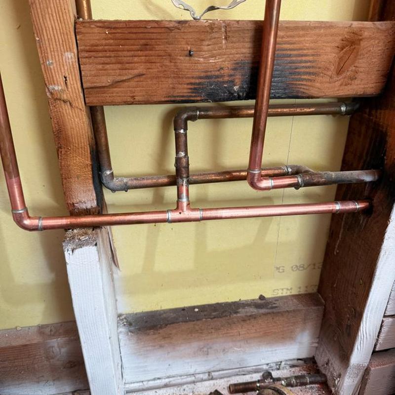 Copper plumbing pipes reworked inside bathroom wall studs