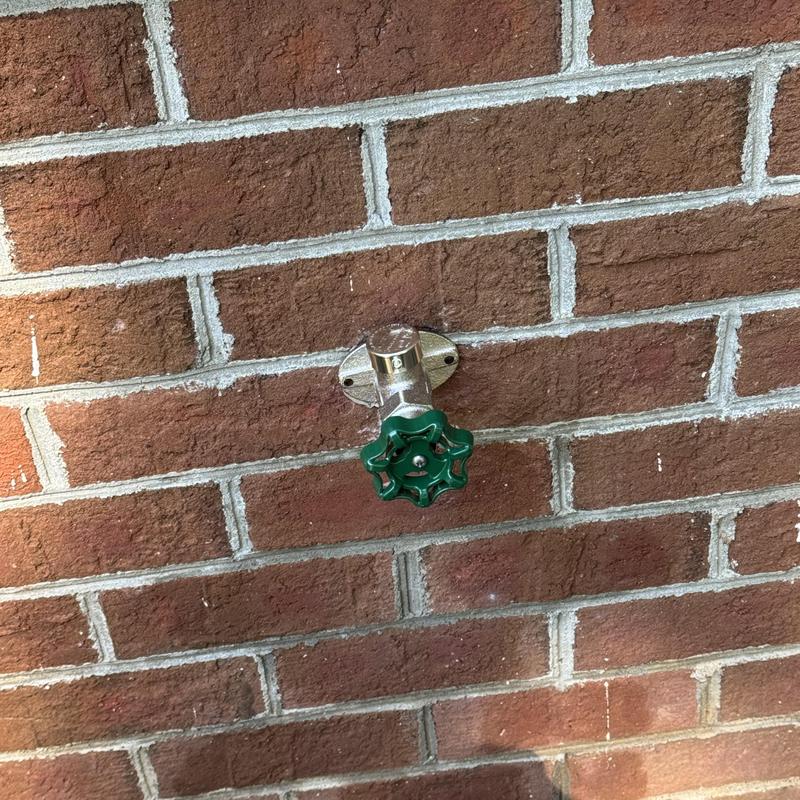 Frost proof outdoor faucet with green handle on brick wall Frost proof outdoor faucet with green handle on brick wall