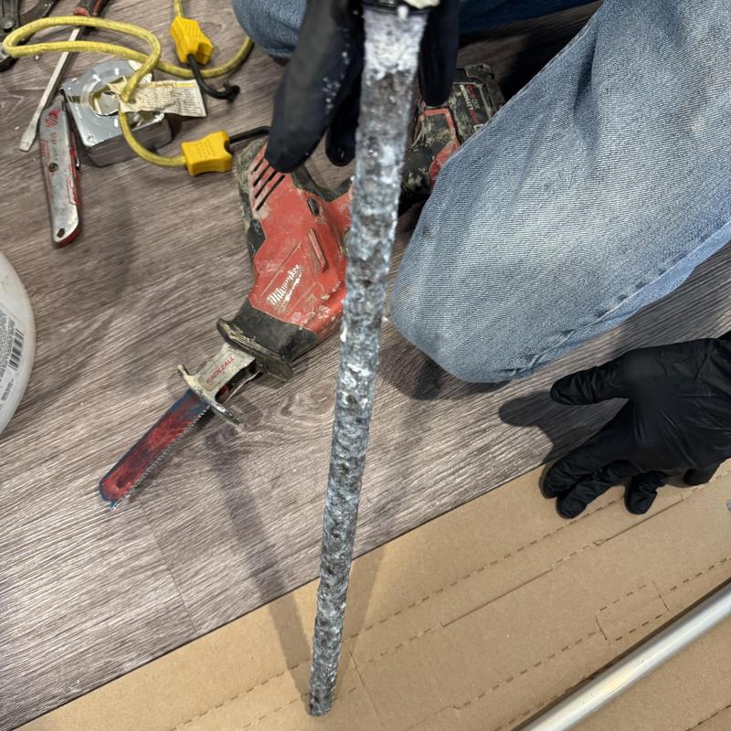 Corroded water heater anode rod held by gloved hand Corroded water heater anode rod held by gloved hand