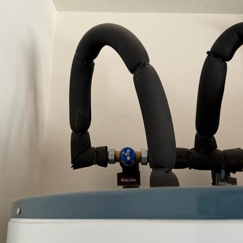 Mixing valve with insulated water pipes above tank