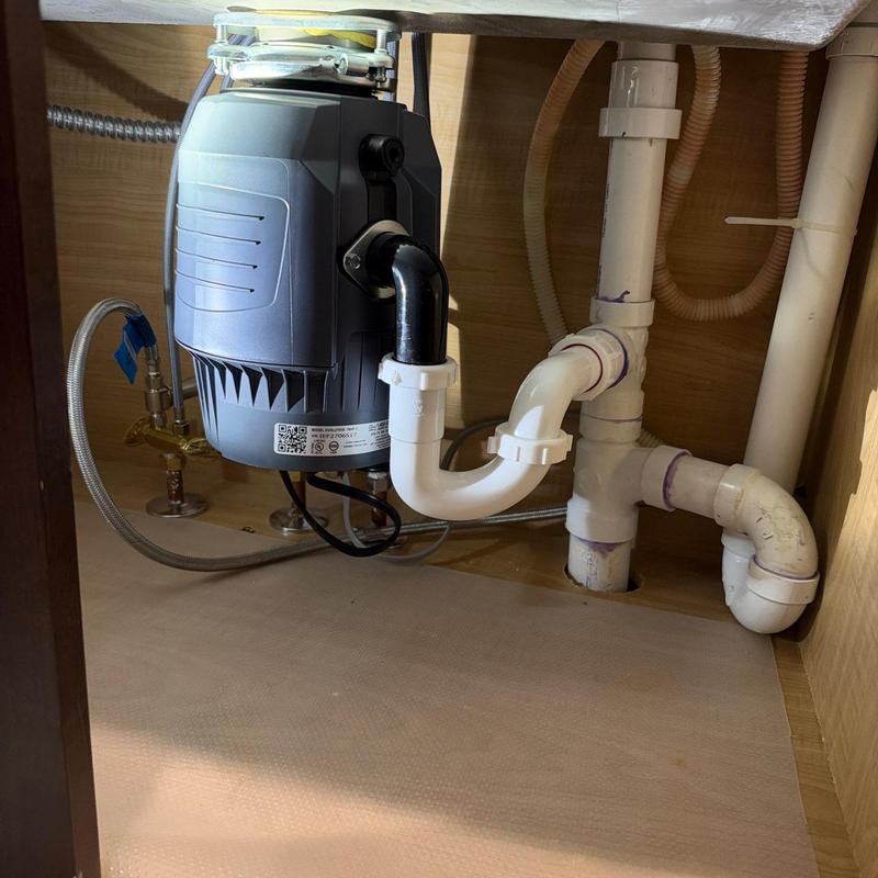 Garbage disposal with connected PVC drain pipes under sink