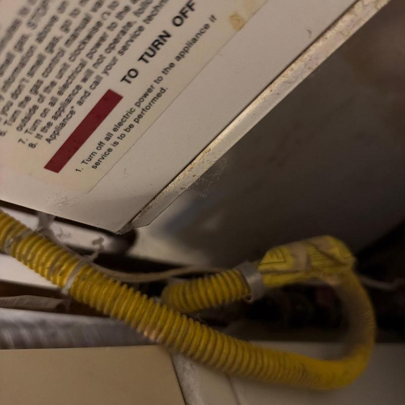 Yellow corrugated gas line connection near appliance